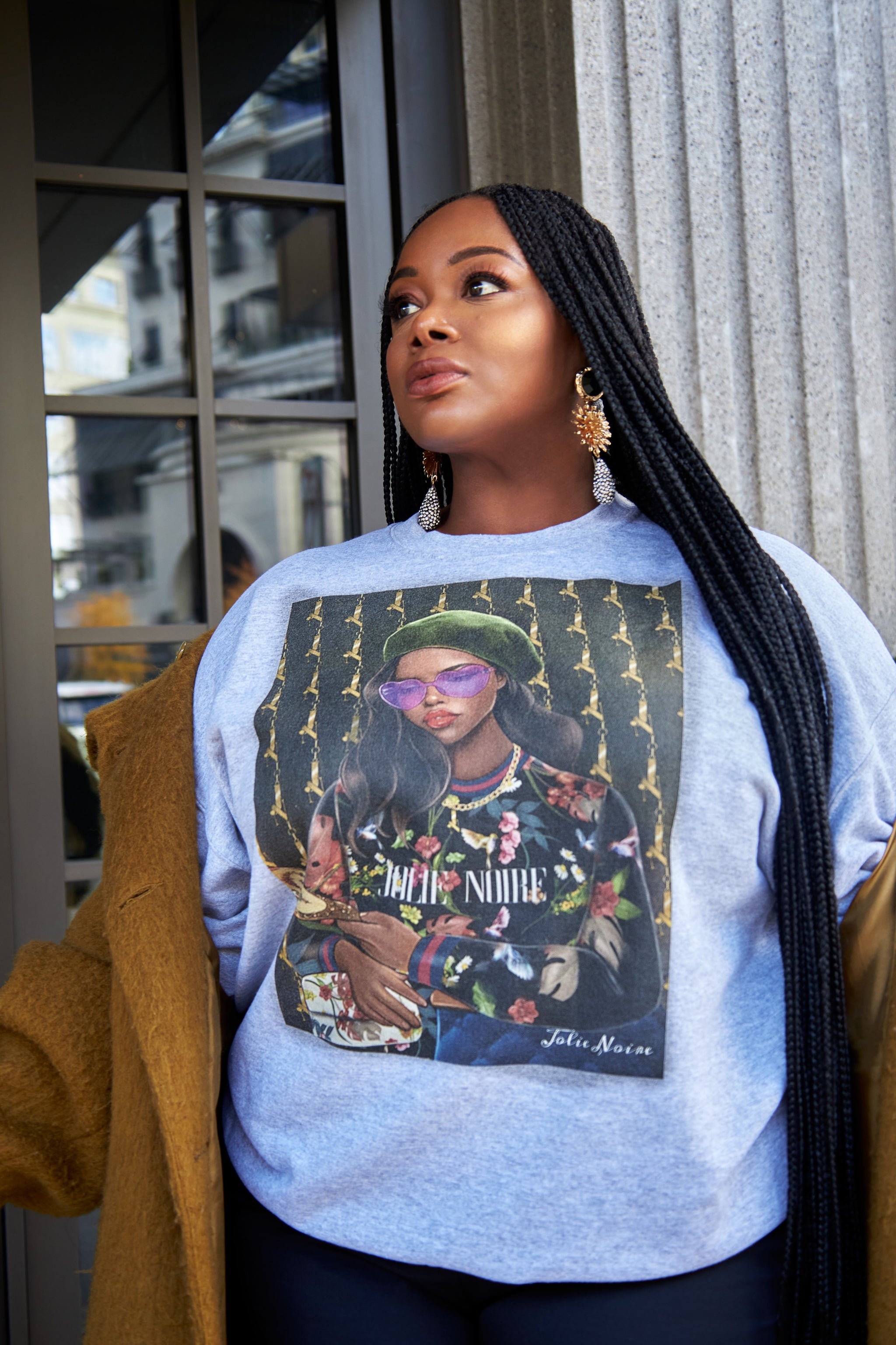 model wearing a gray sweatshirt with a graphic design of a person in a green hat and sunglasses.
