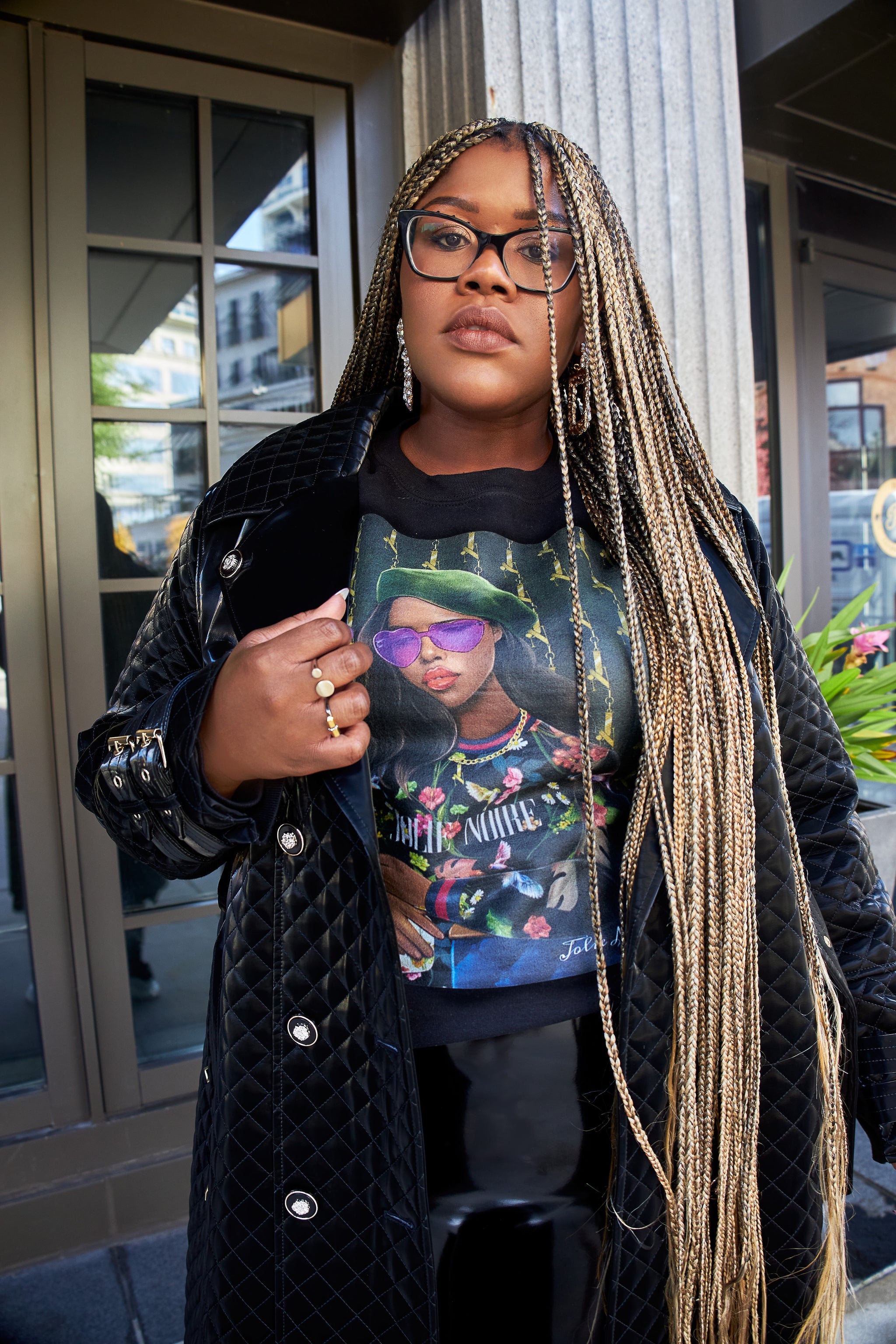 model wearing a black sweatshirt with a graphic design of a person in a green hat and sunglasses.